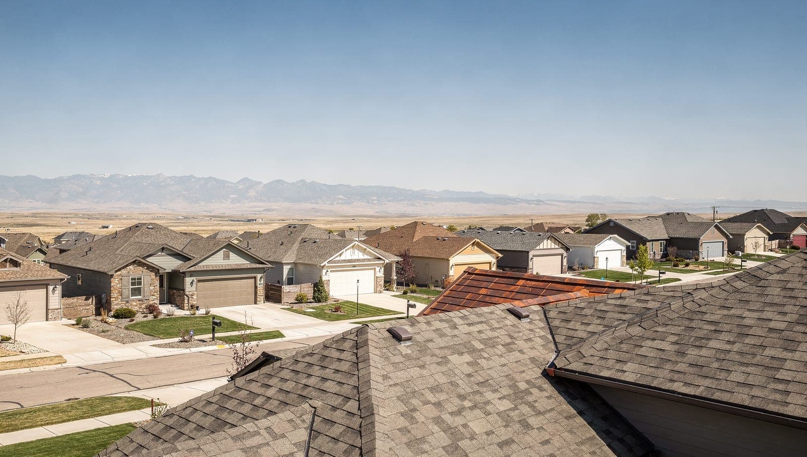 A Centennial neighborhood of homes with asphalt roofs under a wide Front Range sky